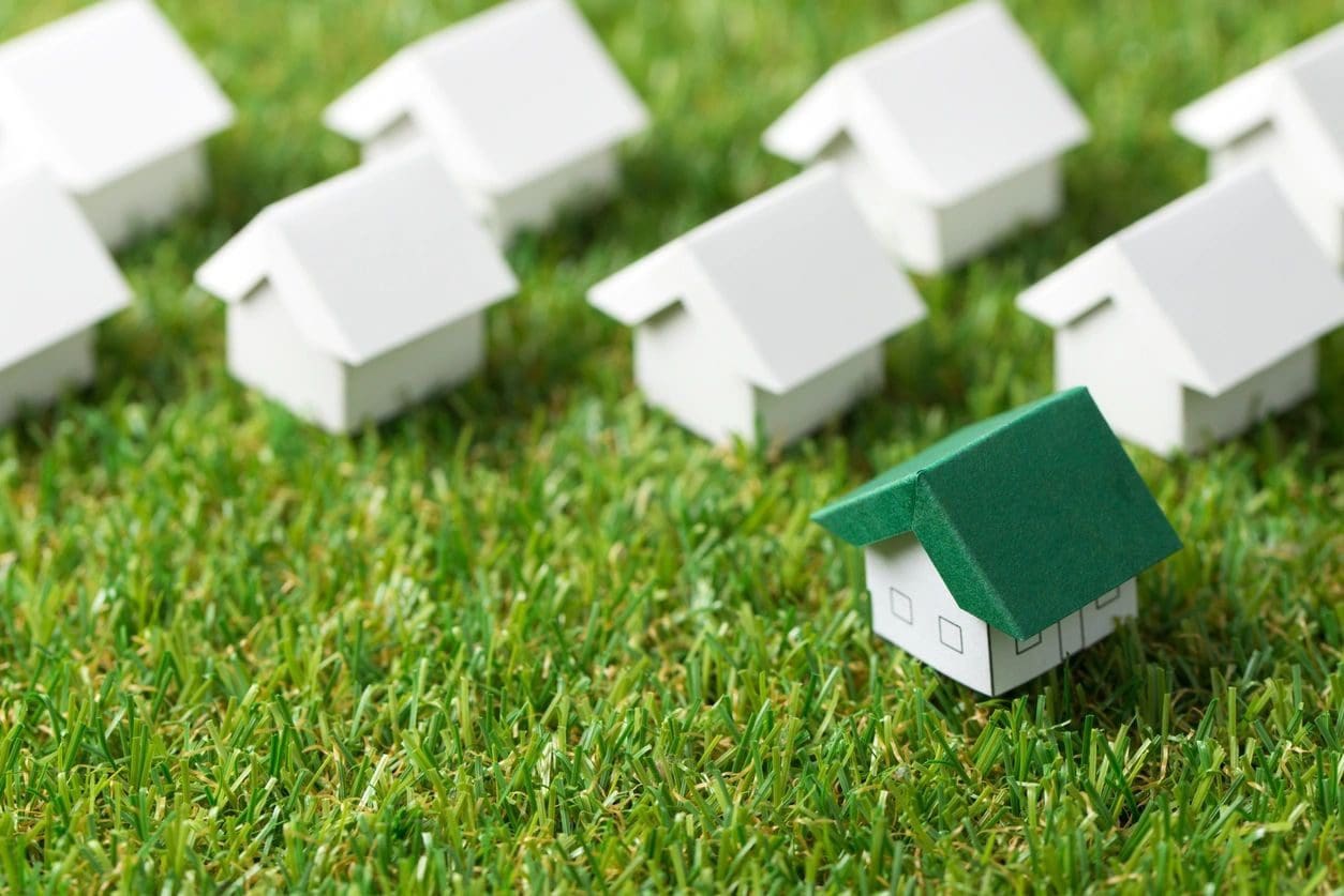 A group of toy houses on the grass.